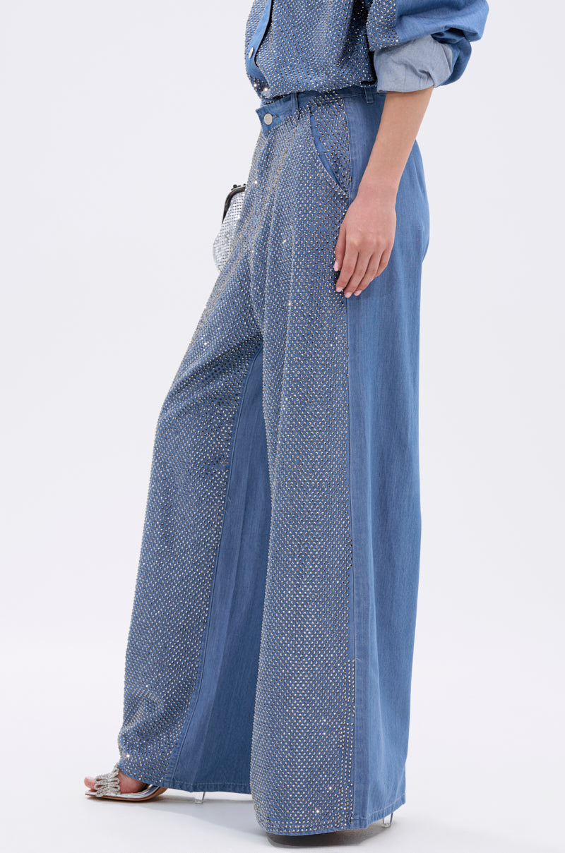 A person wears the BLING BLING DENIM RELAXED PANT with a matching high-rise denim shirt and silver high-heeled sandals, standing against a plain white background.