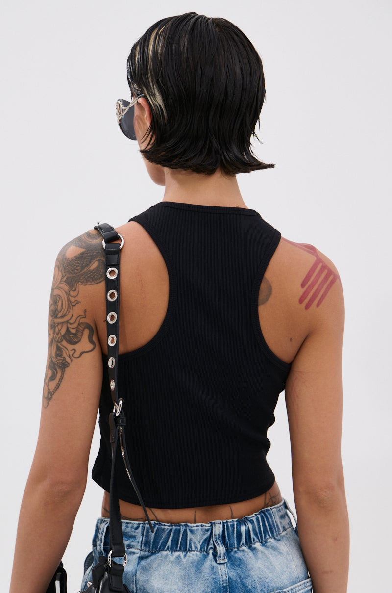 A person with short, dark hair and a blonde streak is seen from behind in blue jeans and the JANE GROMMET TANK TOP, featuring metallic studs. They have tattoos on their left arm and a pink abstract tattoo on their right shoulder. 4