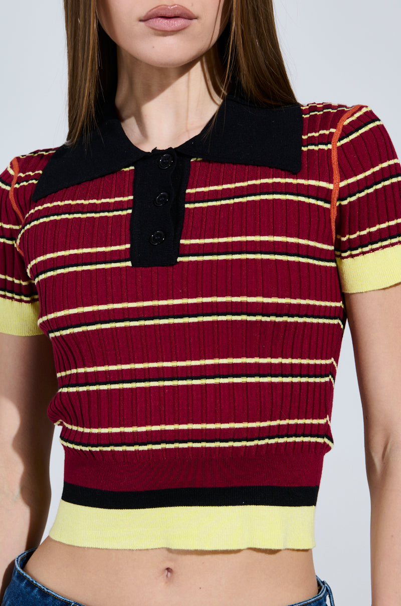 Someone is wearing the SCHOOL GIRL VIBES POLO, featuring a red ribbed knit fabric with black and yellow stripes, a cropped silhouette, a black collar, and front buttons. 6