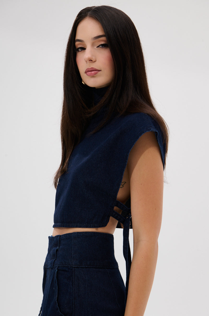 A woman with long dark hair models the YOU A REAL ONE DENIM BLOUSE and high-waisted jeans, standing sideways against a plain light background with a neutral expression.