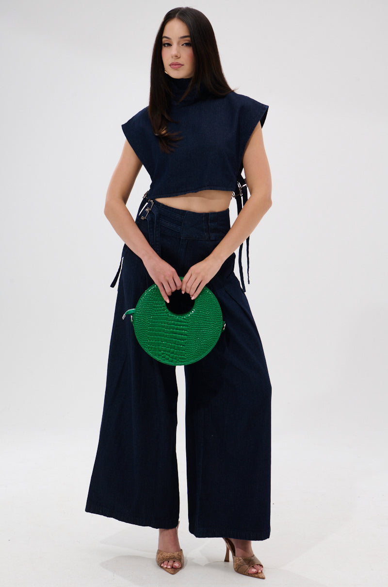 A woman stands against a white background wearing the YOU A REAL ONE DENIM BLOUSE and matching wide-leg pants, holding a round green handbag and sporting gold open-toe heels.