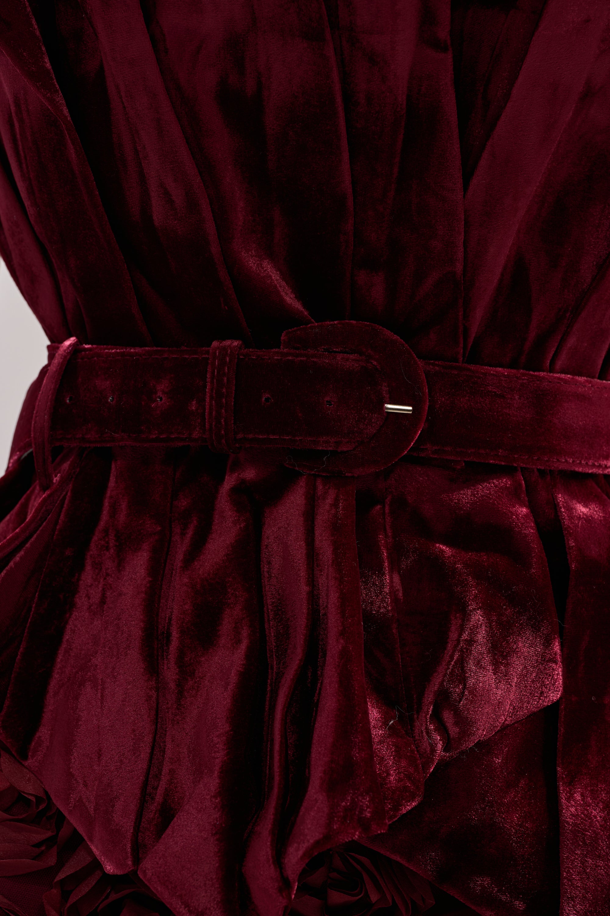 A close-up of the DRAMA DRAMA DRAMA VELVET BLOUSE in deep red velvet, showcasing its matching belt with rounded buckle, gathered and draped details, and plush, rich texture.