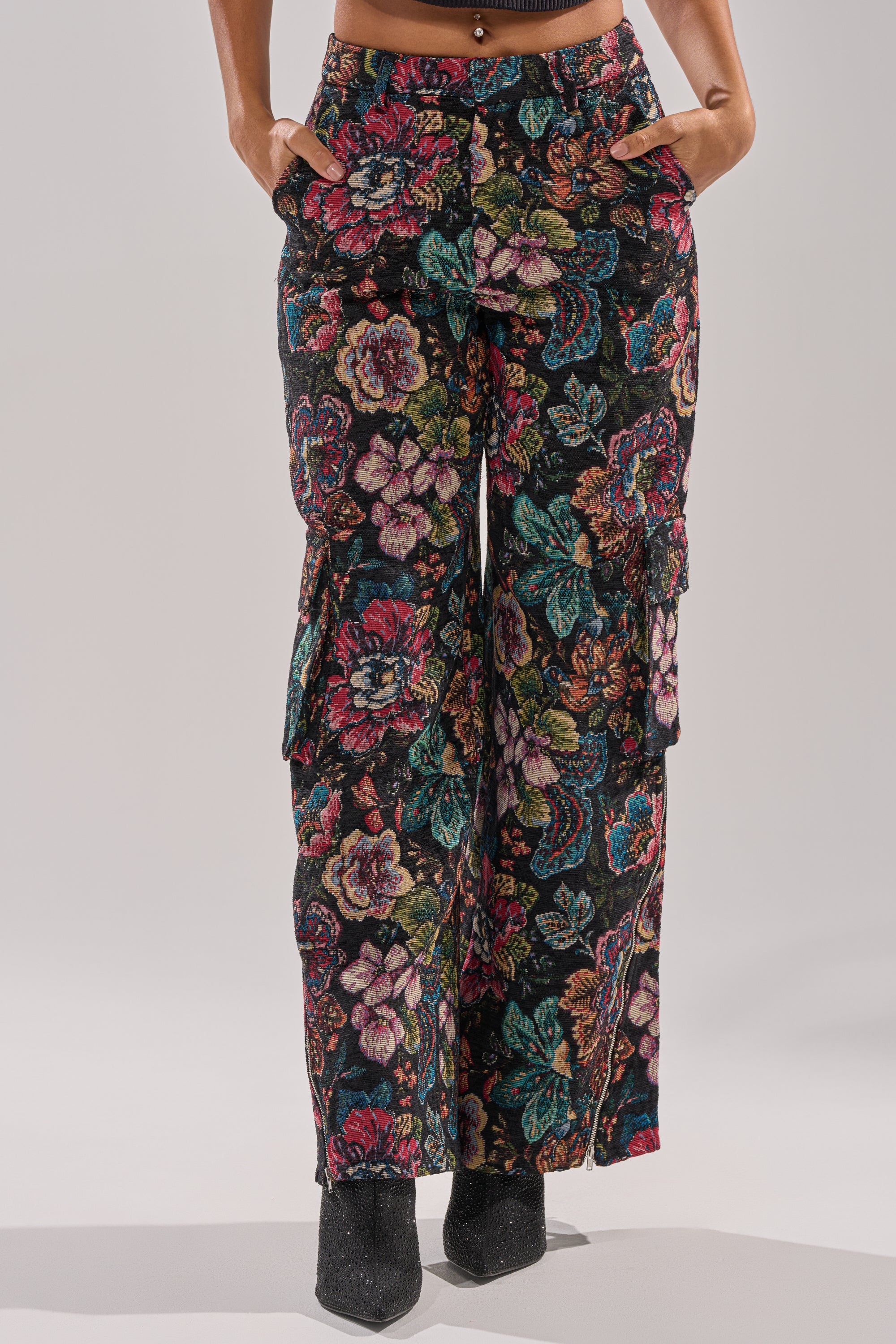 Wearing the PRETTY LITTLE LADY BROCADE TROUSER, featuring a high-rise wide-leg fit, colorful floral pattern, and side pockets, this look is completed with black pointed-toe shoes.