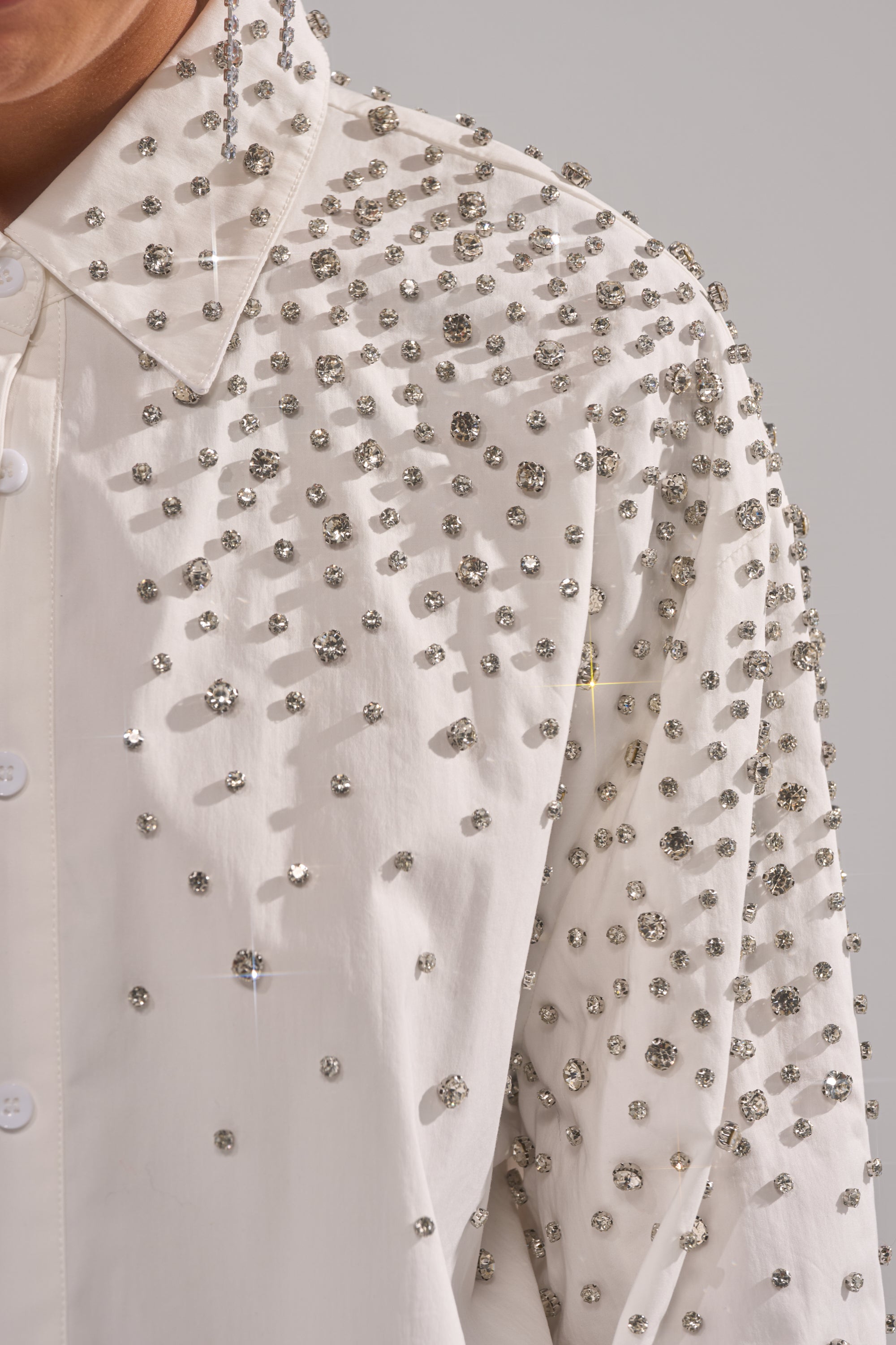 Close-up of the DIAMONDS FOREVER BUTTON DOWN, a tailored women's shirt featuring sparkling rhinestones on the collar, shoulders, and upper sleeves for a glamorous, textured look.
