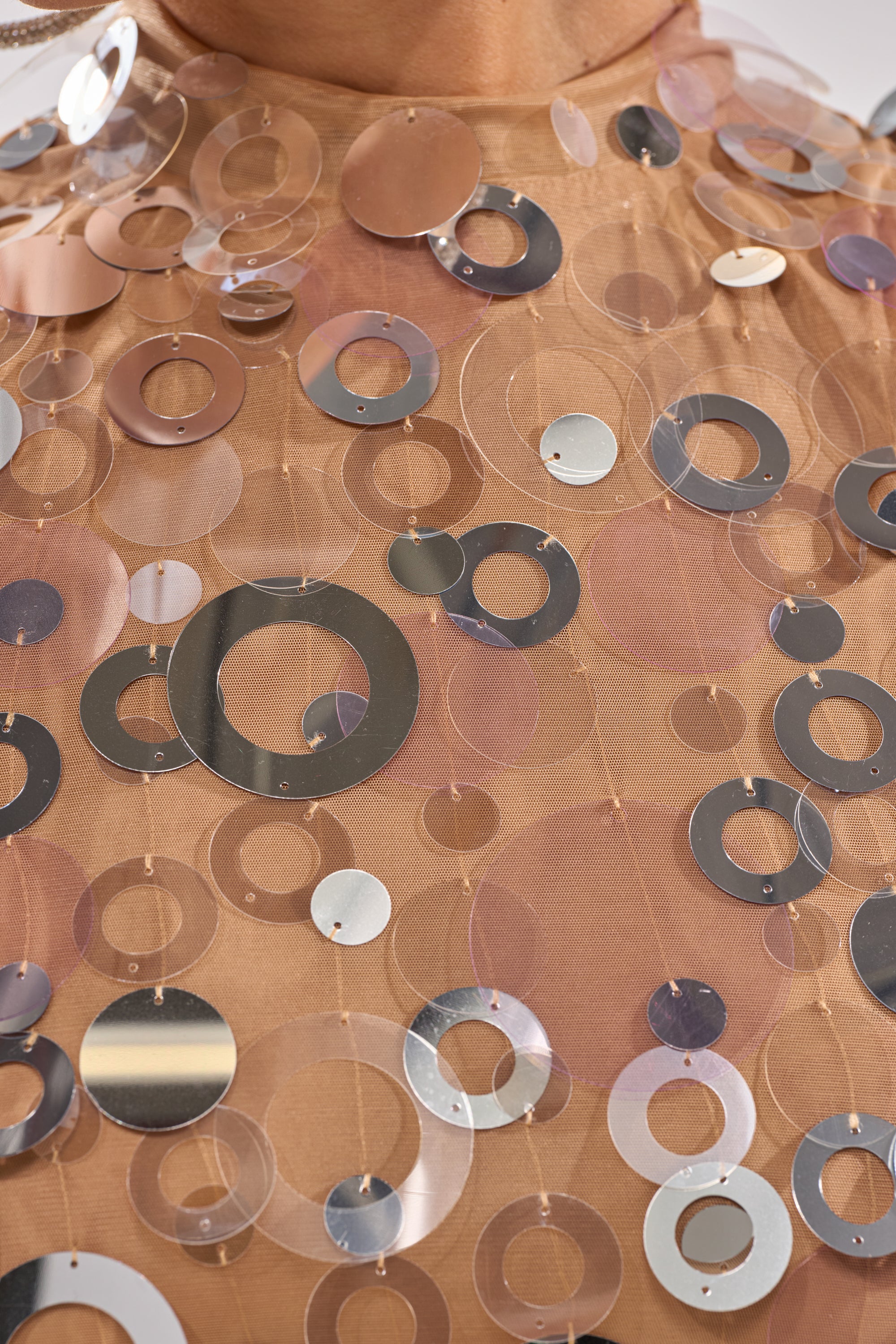 Close-up of the BLING BLING TANK, a nude mesh tank top embellished with shiny metallic sequins in various sizes. The reflective appliqué creates a dazzling, eye-catching look—perfect for parties. 5