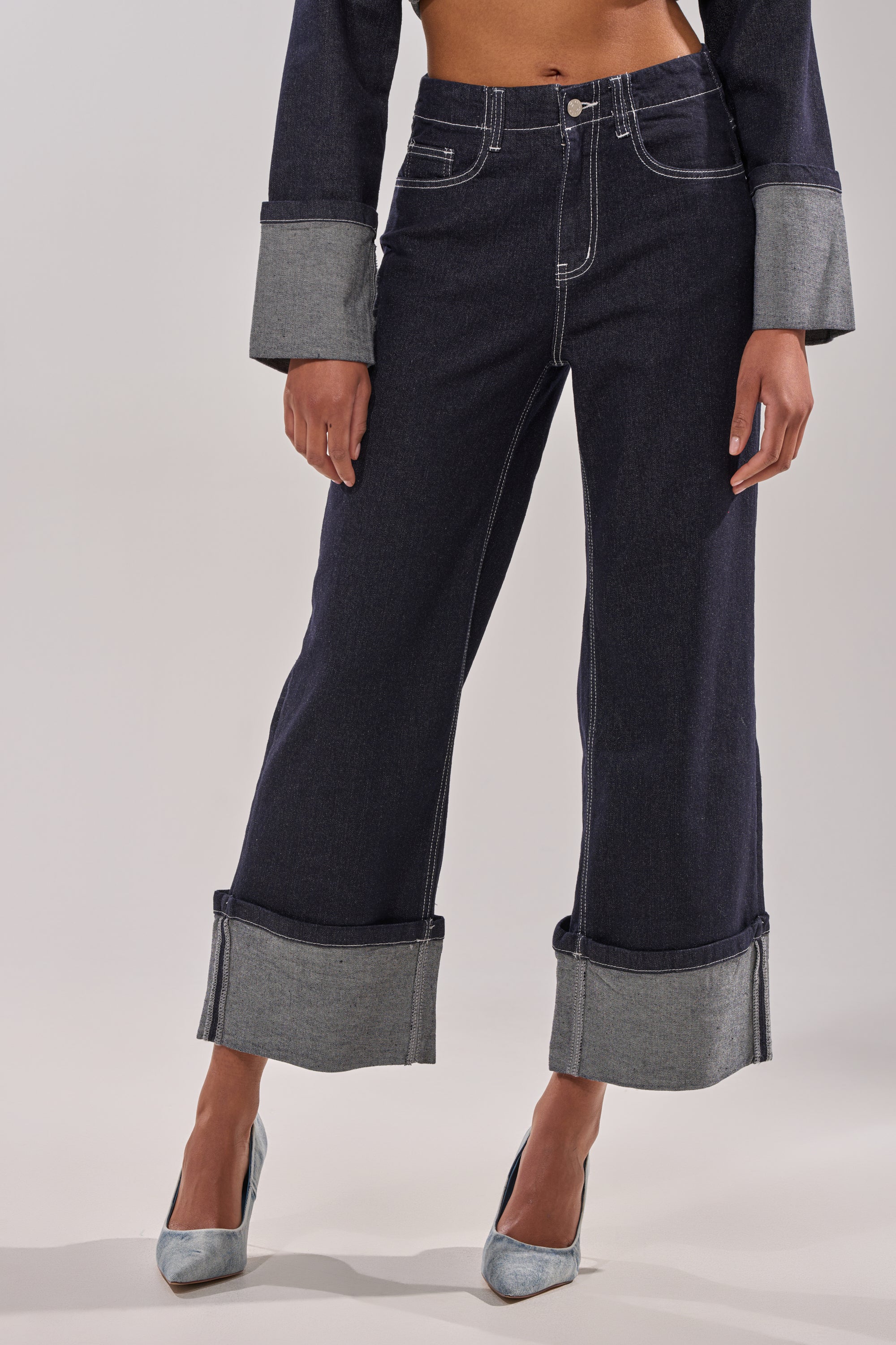 A person wears DON'T TALK TO ME WIDE LEG DENIM JEANS with large, high-contrast cuffs and light gray pointed-toe heels; the image is cropped from the shoulders down. 2