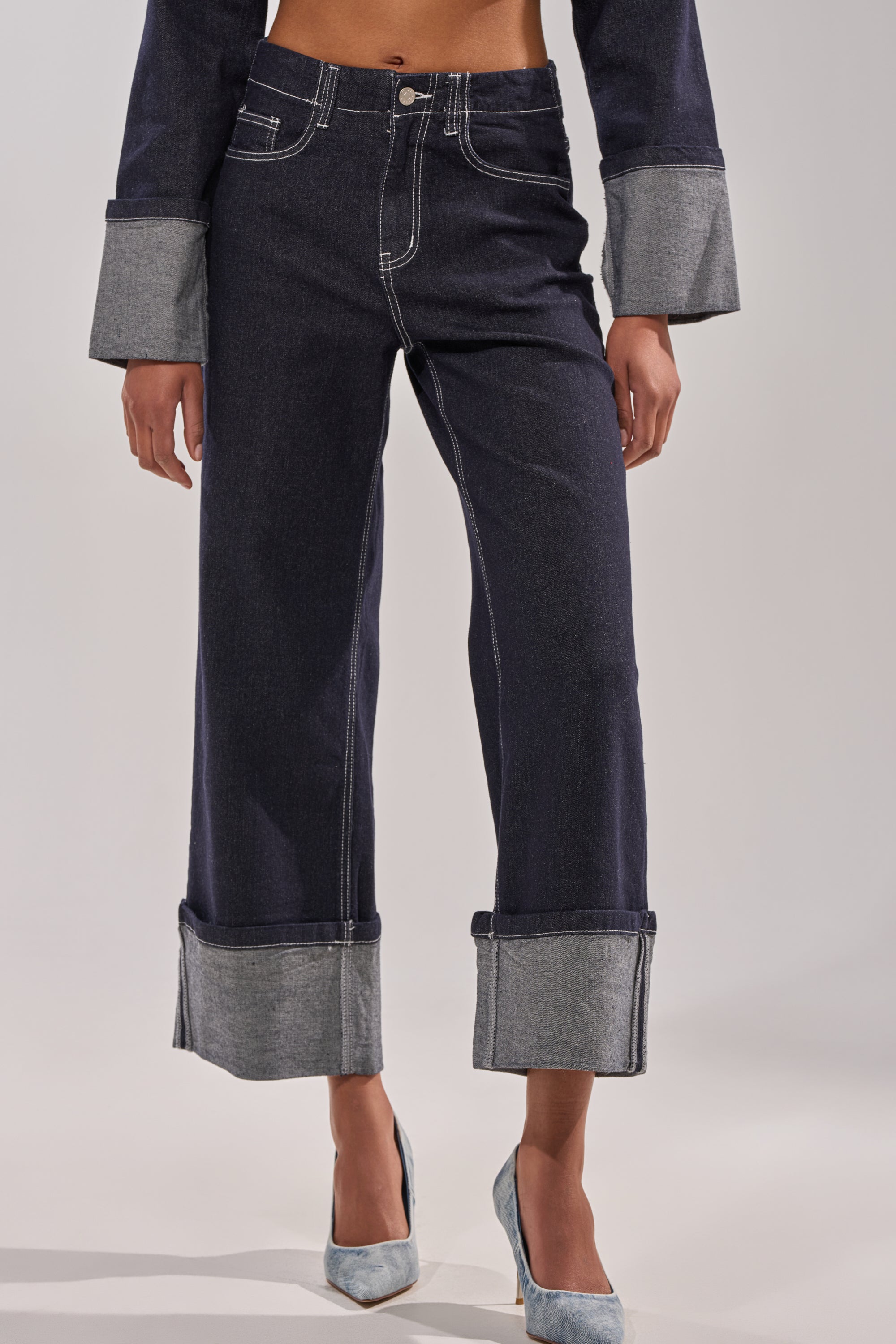 A person wears DON'T TALK TO ME WIDE LEG DENIM JEANS with a high-rise waist and turned-up cuffs, styled with a matching long-sleeve top and light blue pointed-toe heels against a plain light background. 3