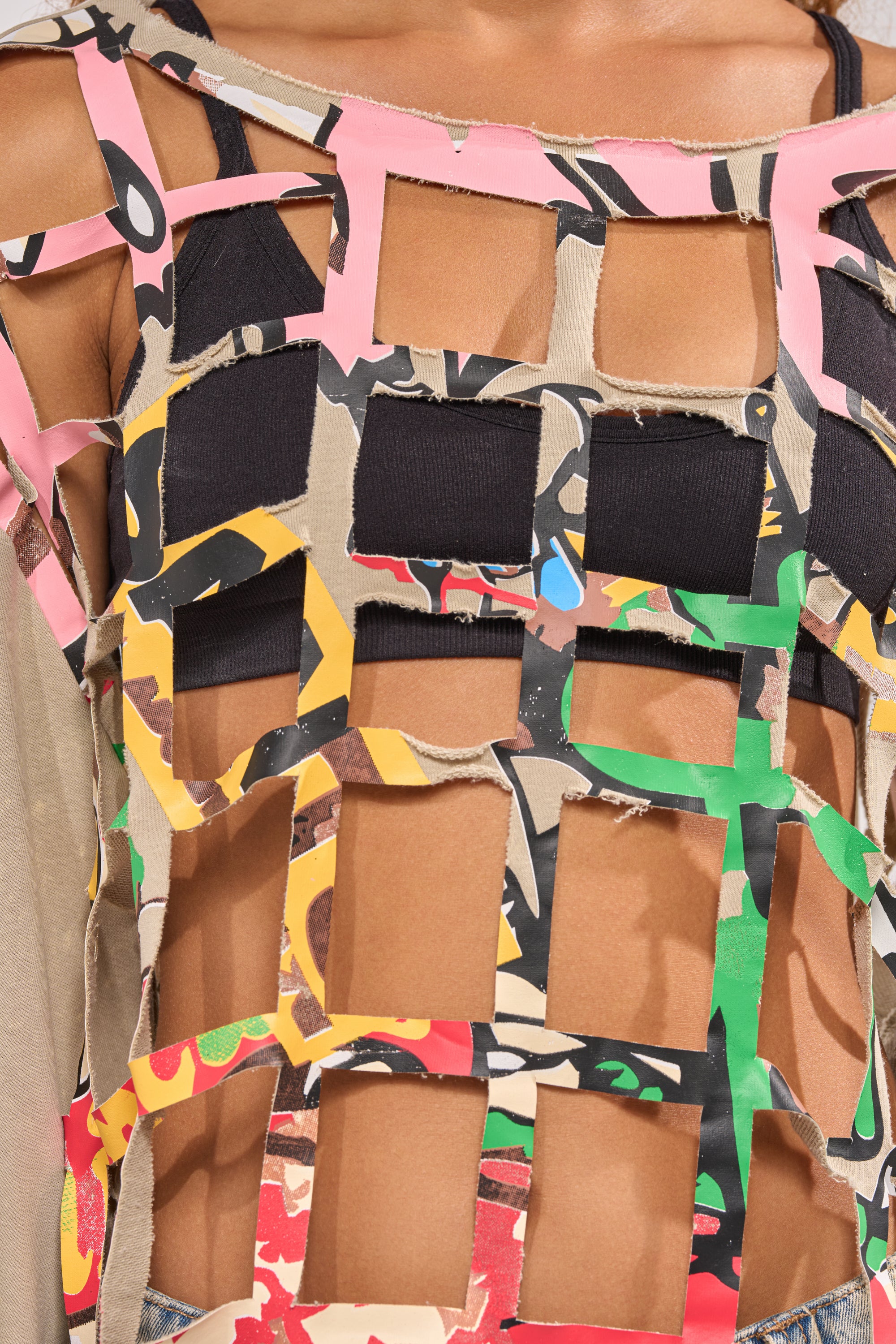 A close-up of someone wearing the CAGED UP LONG SLEEVE GRAPHIC TEE, featuring bold cutouts and colorful graphics layered over black for standout streetwear style. 7