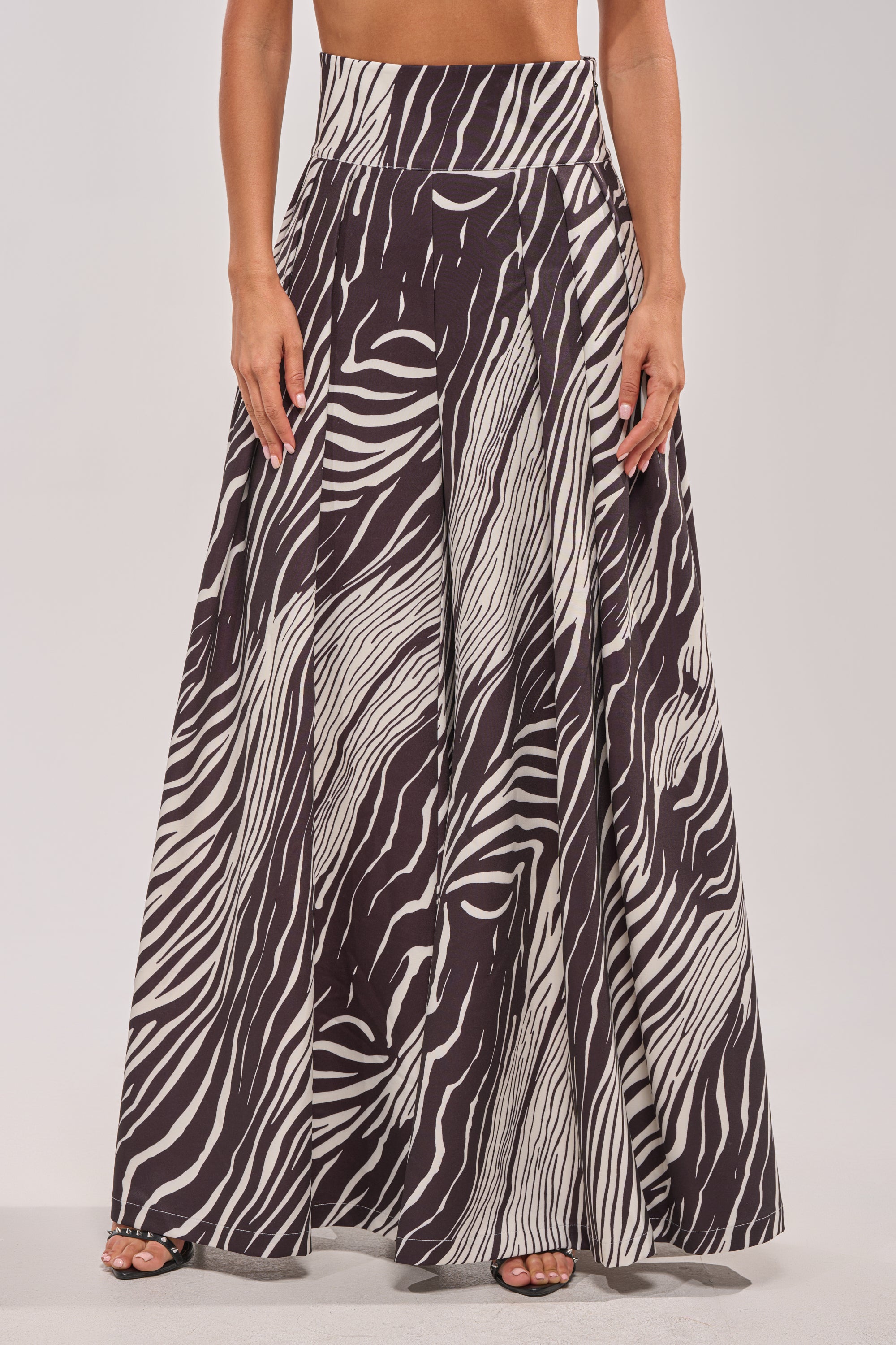 Wearing the WILD AND FREE ZEBRA TROUSER, someone strikes a bold wide-leg silhouette in black and white zebra print against a plain light background.