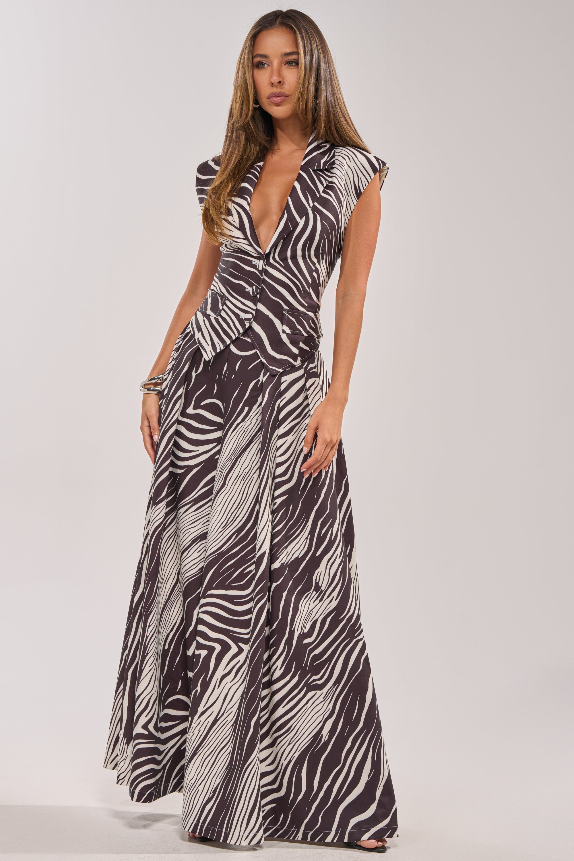 Woman wearing WILD AND FREE ZEBRA TROUSER with a bold black and white zebra print. The high-rise waist flatters her silhouette, while the wide-leg style adds drama. She stands confidently against a plain background.