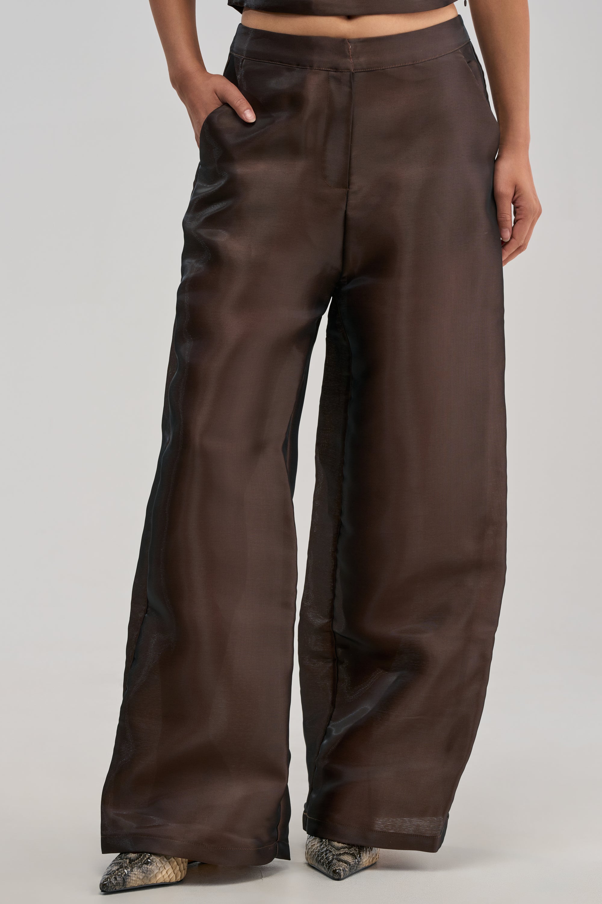 A person wearing the ON FIRE TROUSER IN BROWN—a sheer, wide-leg style with pockets—stands against a light background.