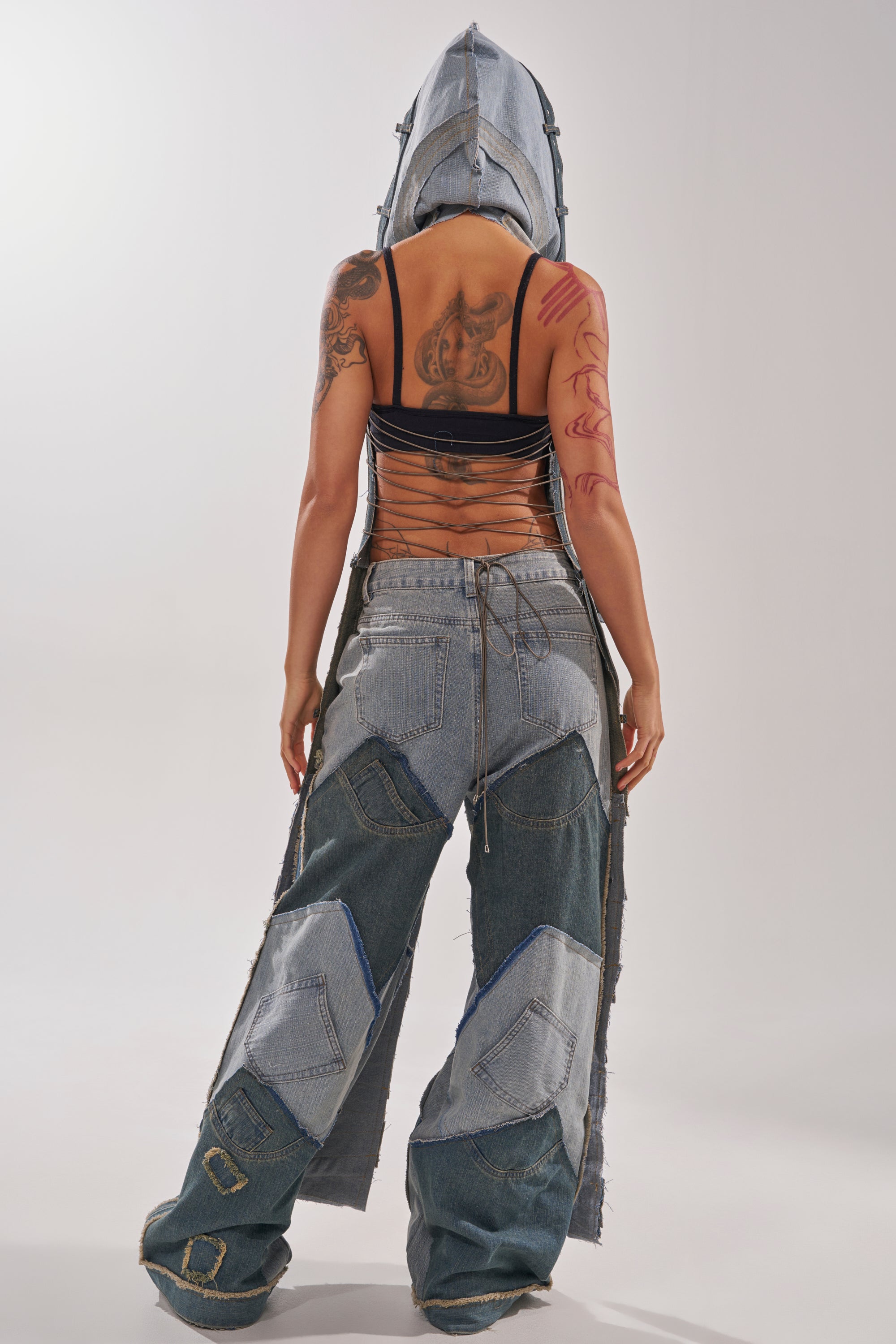 A person faces away, wearing the ALL THAT DISTRESSED HOODED TOP over a strappy black crop top. Their arms and back tattoos are visible, set against a plain light background. 5