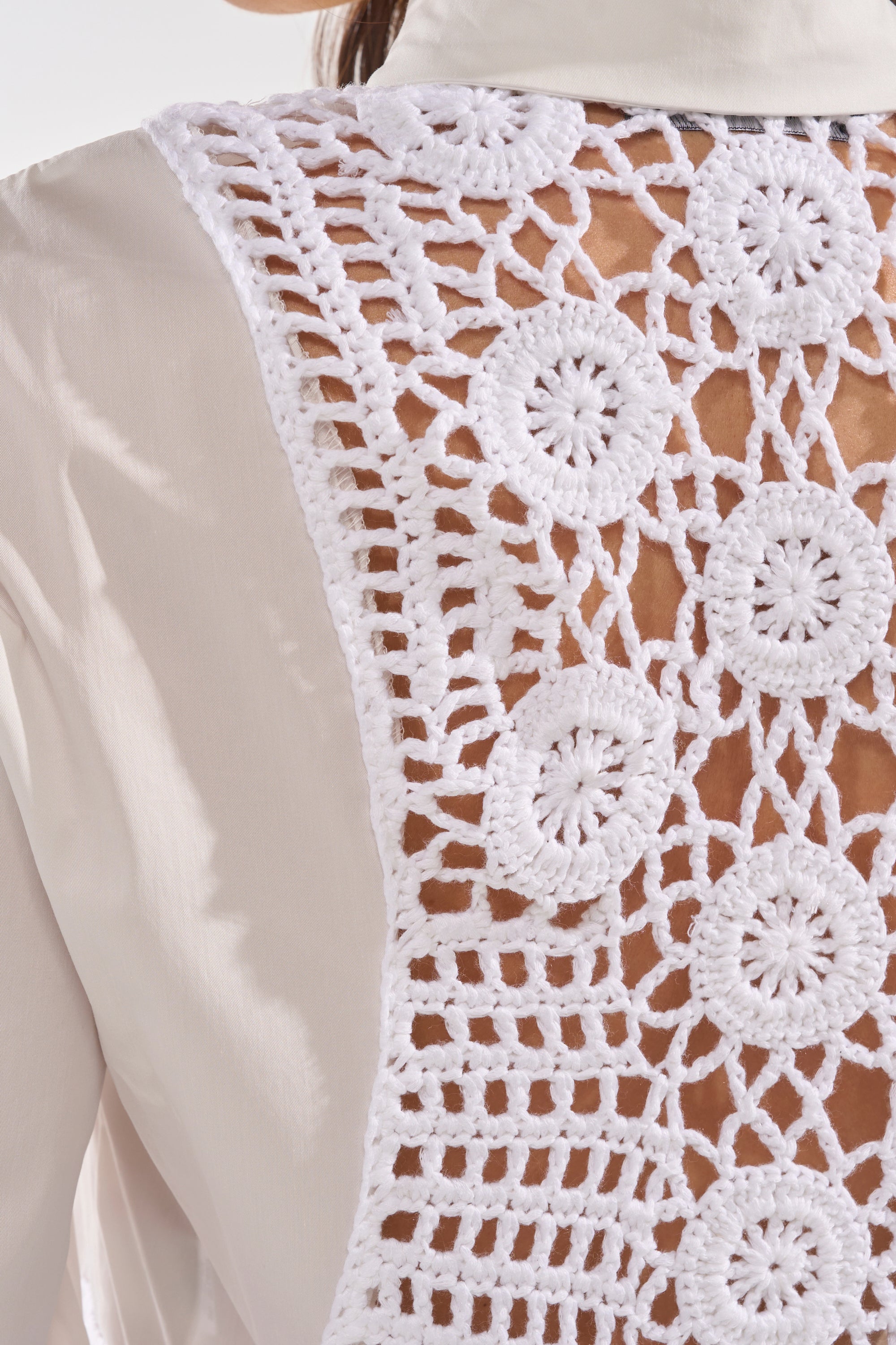 Close-up of the PETAL DRIFT CROCHET DETAIL BLOUSE’s cream crochet fringe back, featuring an intricate white lace panel with circular and geometric designs—perfect for festivals and subtly revealing skin underneath. 5