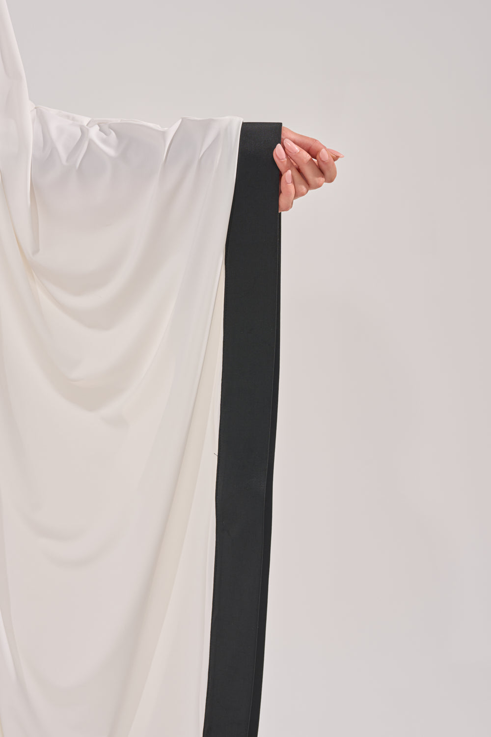 A hand extends outward, partly covered by the flowing sleeve of the GUEST OF HONOR BODYCON MAXI DRESS featuring a wide black border, set against a plain, light background. 6