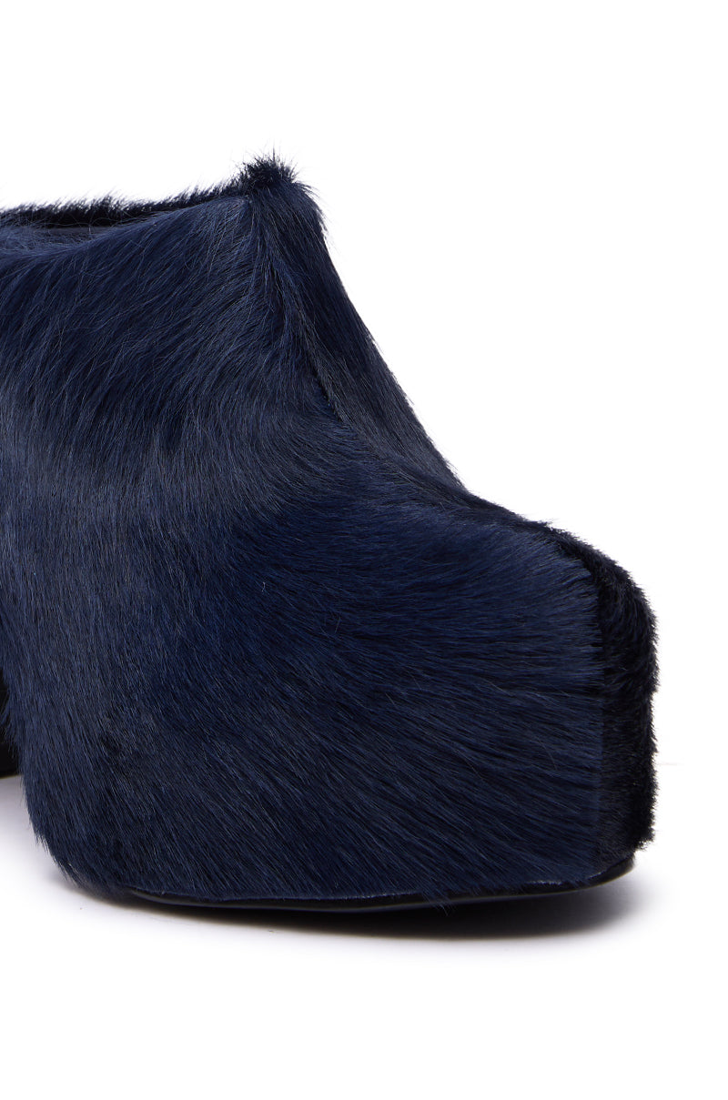 A close-up of the AZALEA WANG GOLDING NAVY PONY HAIR CHUNKY PUMP, featuring dark blue faux fur, a chunky block heel, and a rounded toe, displayed against a white background. 7