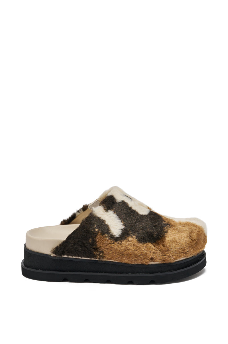 The AZALEA WANG GOVINDA MULTI SLIP ON COW PRINT CLOG features a brown, black, and white patterned upper, beige footbed, and black sole, shown in a side view against a white background.