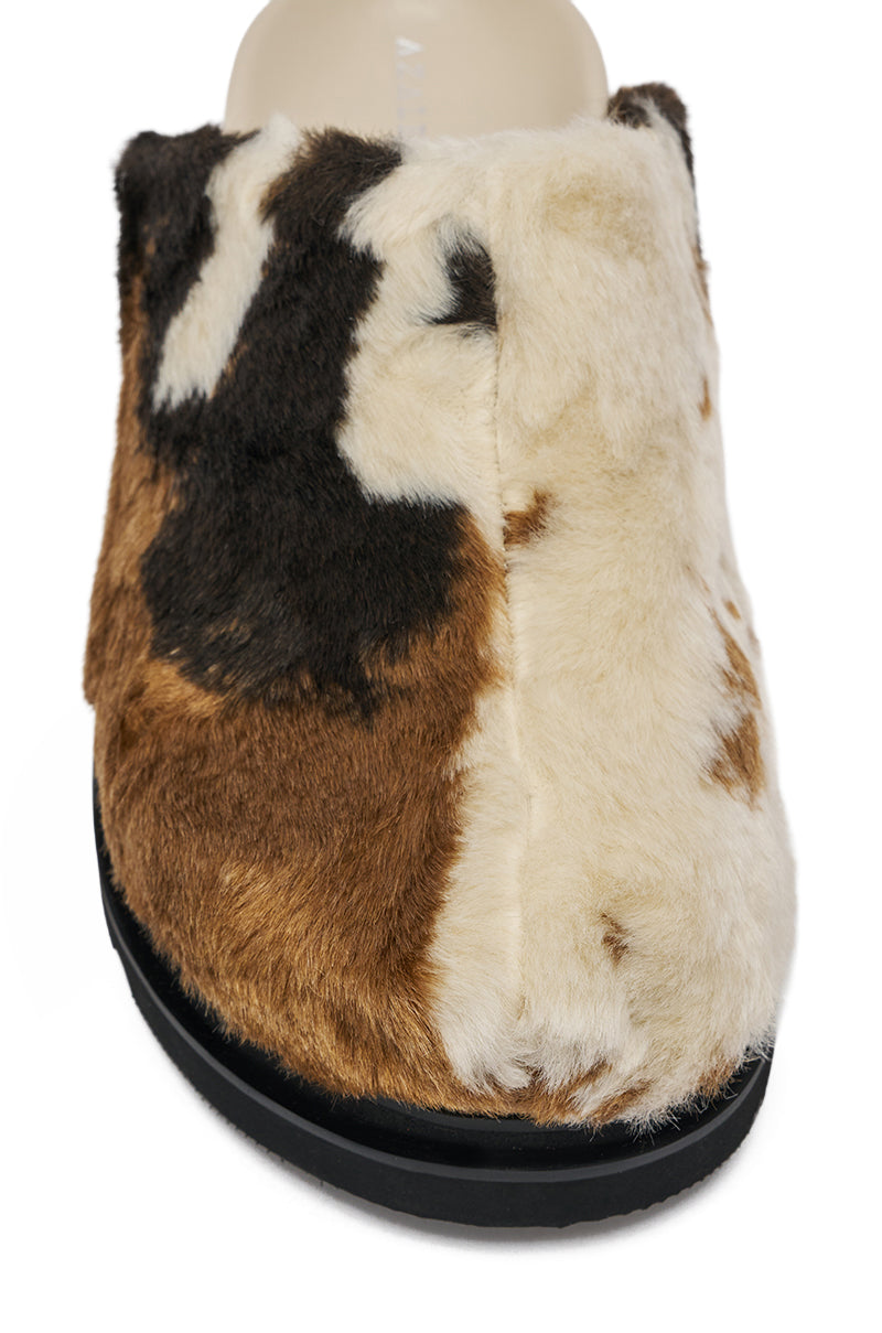 Front view of the AZALEA WANG GOVINDA MULTI SLIP ON COW PRINT CLOG, featuring a fuzzy brown, black, and cream cow print exterior and a sturdy black sole.