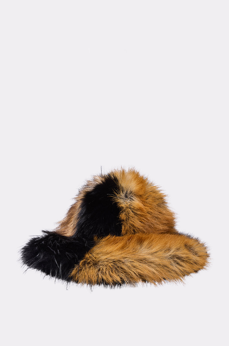 The COSMO FAUX FUR OVERSIZED BUCKET HAT features a black and golden-brown patchwork design in plush faux fur—an eye-catching, cozy accessory for cold weather, photographed against a plain light background.