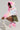 A person crouches while wearing the COTTON CANDY SKIES MULTI FAUX FUR BOMBER along with matching boots. They team the outfit with a green camouflage skirt and hold a white studded bag, all set against a plain light gray background.