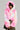 A person is striking a pose in the COTTON CANDY SKIES MULTI FAUX FUR BOMBER, showcasing vibrant shades of pink, white, and pastels. Paired with a camouflage-patterned skirt, the ensemble stands out brilliantly against the plain background.