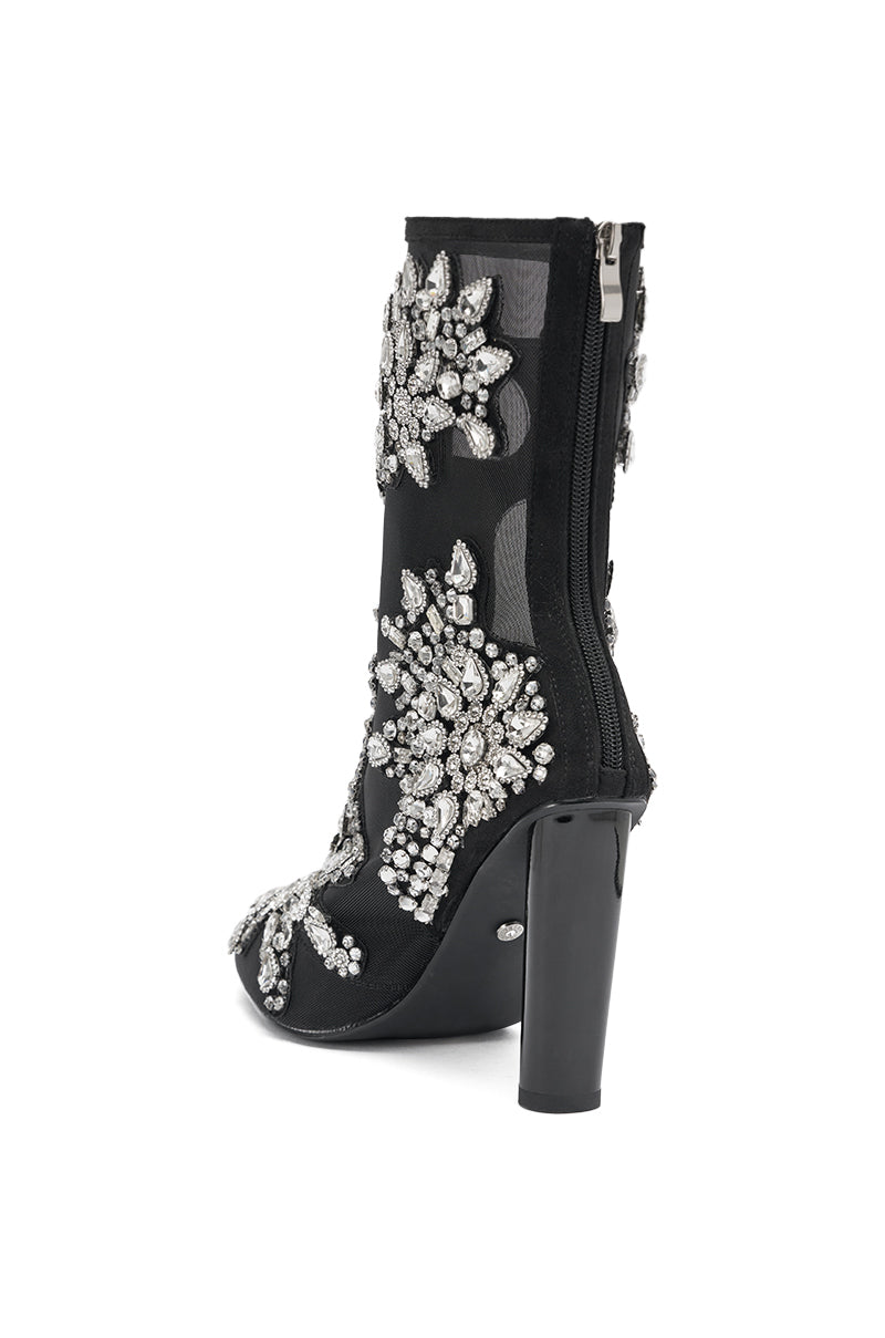 The AKIRA GOLD GRANDEUR BLACK EMBELLISHED COCKTAIL BOOTIE features sheer mesh panels, bold silver rhinestone floral designs, and a visible back zipper.