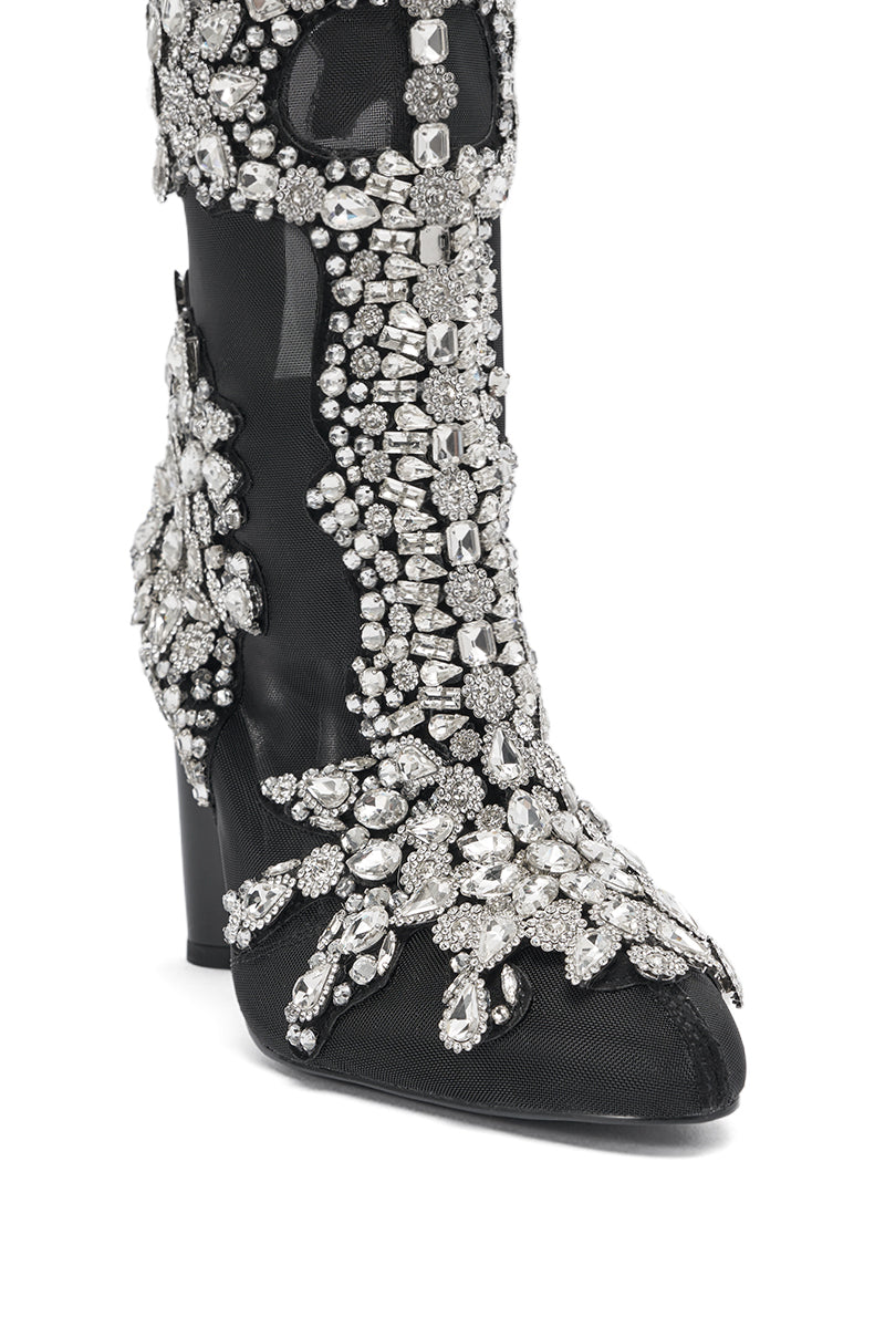 A close-up of the AKIRA GOLD GRANDEUR BLACK EMBELLISHED COCKTAIL BOOTIE, featuring black fabric adorned with clusters of sparkling silver rhinestones and intricate gem embellishments on the front and sides.