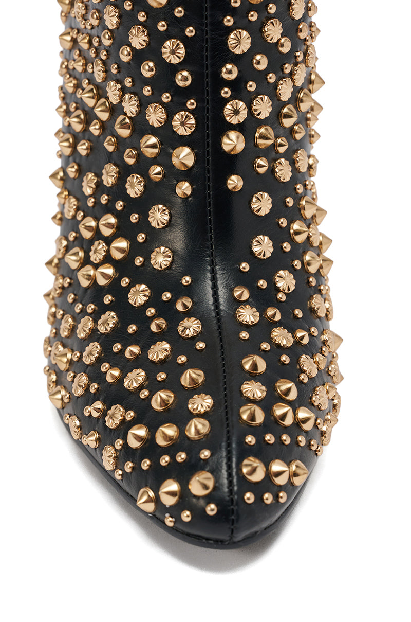 Close-up of the AZALEA WANG GREHGAN BLACK EMBELLISHED CHUNKY HEEL BOOTIE, featuring a faux leather finish adorned with shiny gold studs and spikes in assorted shapes and sizes.