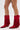A person models the AZALEA WANG GREIA RED RHINESTONE COWBOY BOOTIE—sparkly red, faux suede booties with fringe and pointed toes—against a white background, revealing part of a leg tattoo above the left boot.