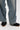 A person wearing loose-fitting blue jeans and AZALEA WANG GREYI BLACK PUFF FLORAL FLAT SNEAKERS stands on a light-colored floor.