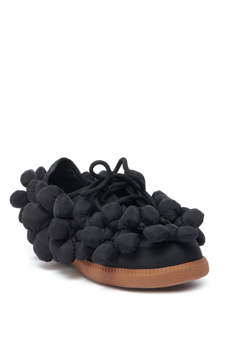 The AZALEA WANG GREYI BLACK PUFF FLORAL FLAT SNEAKER features a bold, black design with soft puffy floral bubbles on the upper, black laces, and a brown rubber sole—perfect for making a statement.