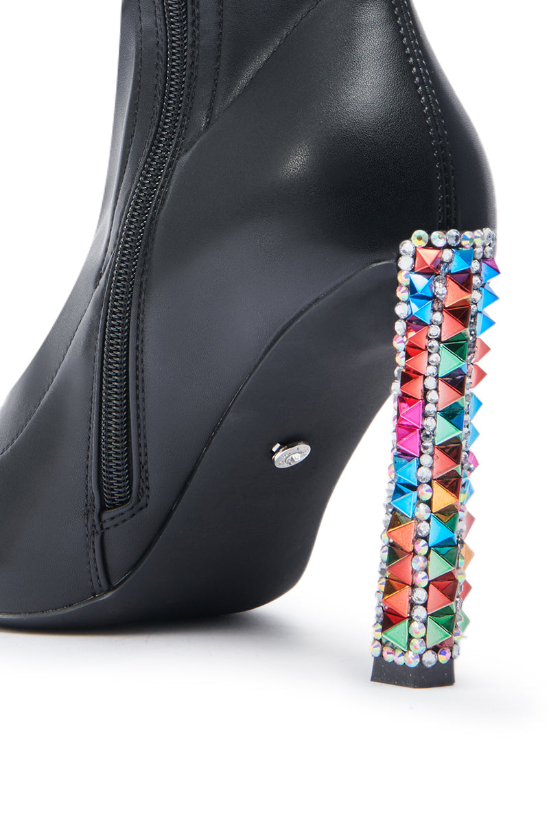 Close-up of the AZALEA WANG GRYFFON BLACK STILETO BOOTIE in faux leather, with a side zipper, high heel decorated with rainbow spike studs, and a border of small rhinestones.