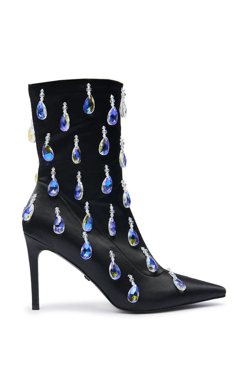 The AZALEA WANG GUANTLETT BLACK CRYSTAL EMBELLISHED BOOTIE features a stiletto heel with rows of dangling blue and yellow teardrop gems and clear crystals, shown on a white background.