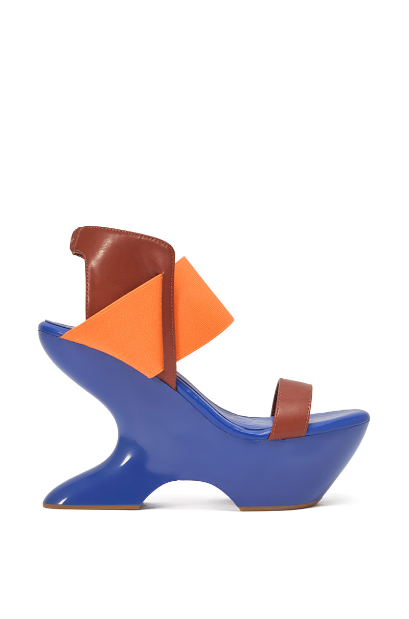 The AKIRA GOLD GUILLAUME BLUE MULTI NOVELTY COLOR BLOCK WEDGE SANDAL features a high platform blue sculptural base, brown leather straps, and an orange accent—creating a futuristic, artistic look that's perfect for making a statement this summer. 2