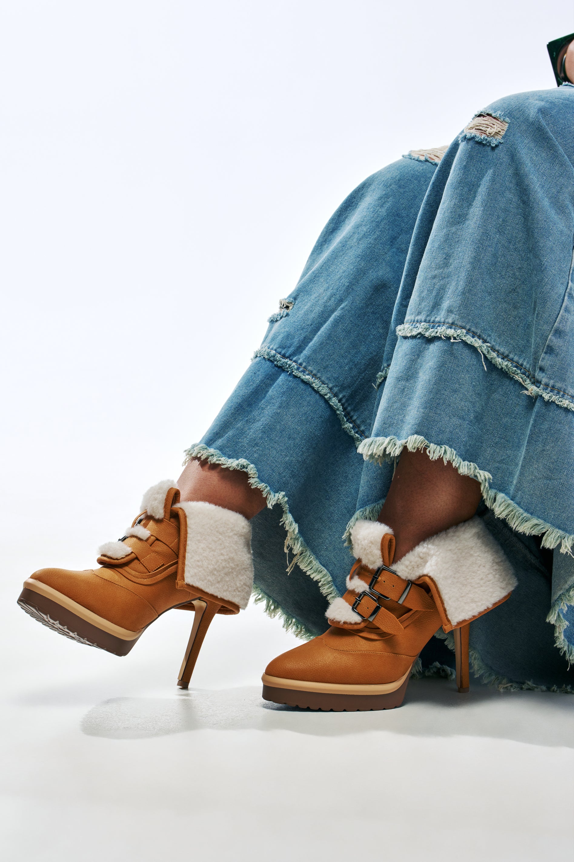 AKIRA GOLD GUST TAN SHERPA LINED STILETTO BOOTIE in tan leather with white faux-shearling cuffs and double buckle straps.