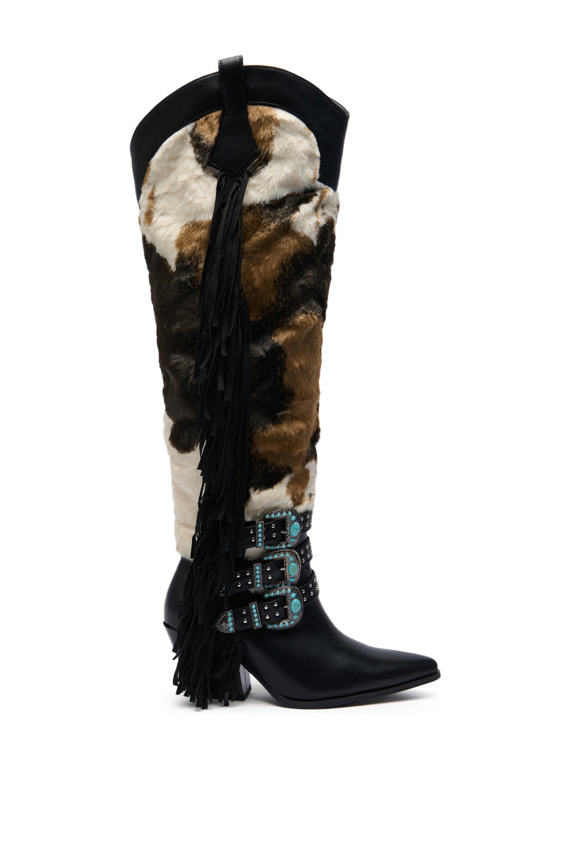 The AZALEA WANG GWAYNE BLACK MULTI COW WESTERN BOOT features a knee-high cowhide pattern, black pointed toe, three blue-studded buckle straps, and bold black leather fringe for standout Western style.