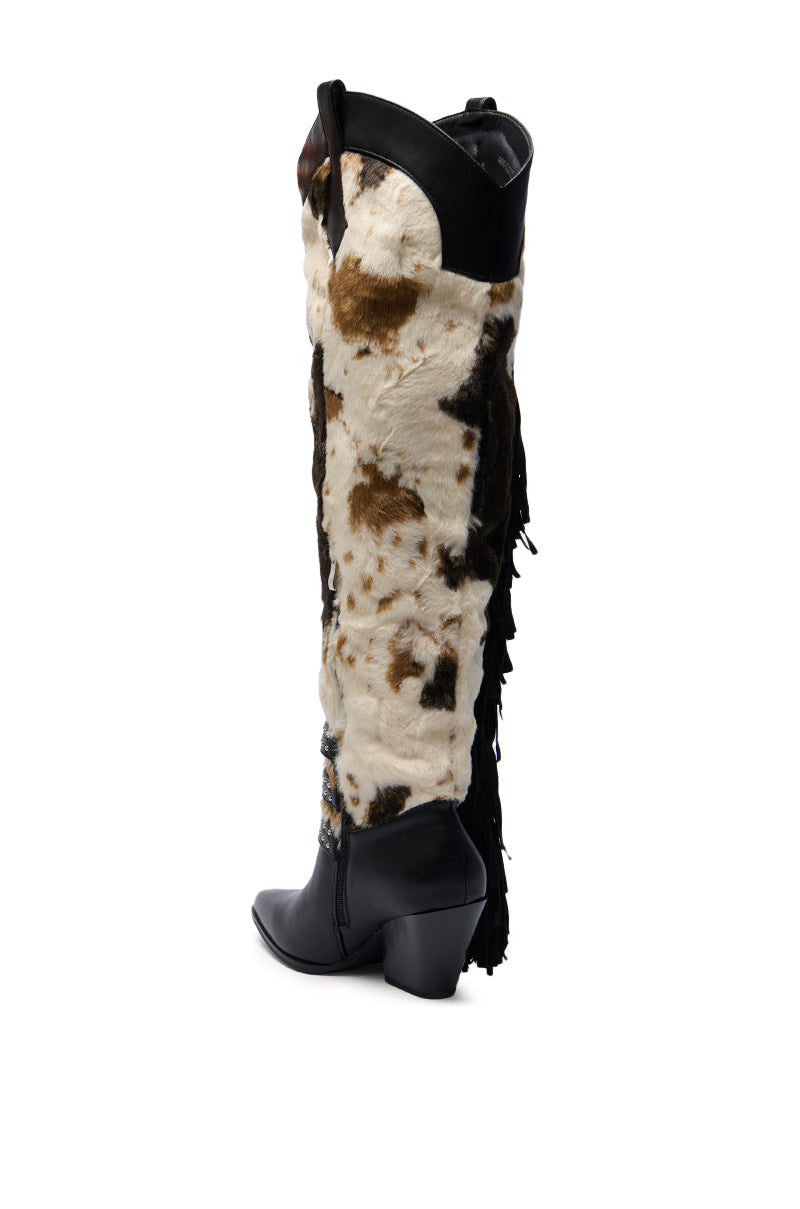The AZALEA WANG GWAYNE BLACK MULTI COW WESTERN BOOT is a tall, knee-high western boot with a black leather foot and trim, brown and white cowhide shaft, and black fringe accents, displayed on a white background.