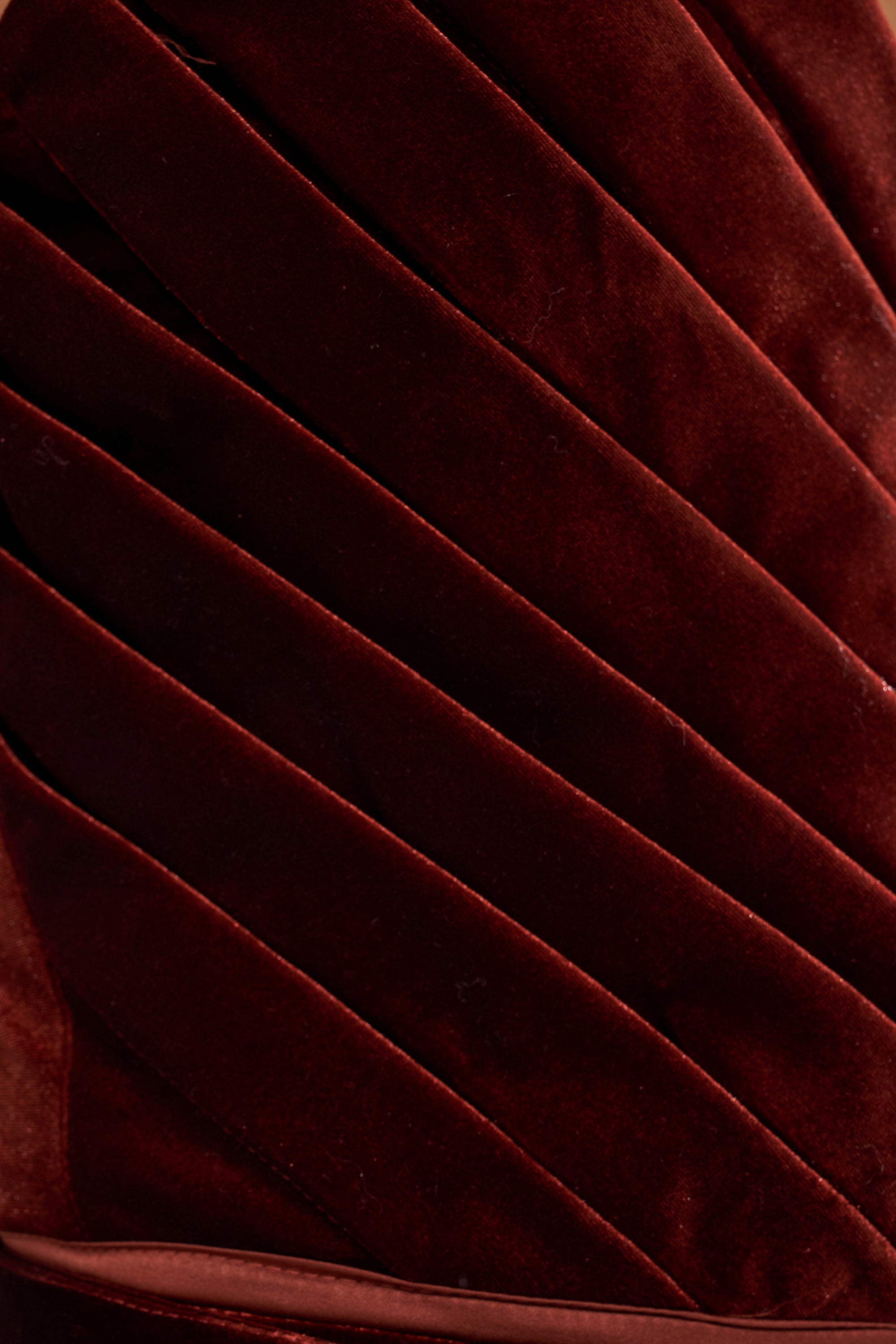 Close-up of the FLASHING LIGHTS VELVET CORSET in rich burgundy velvet with diagonal, padded ridges highlights its plush texture, creating a luxurious and sculptural silhouette.