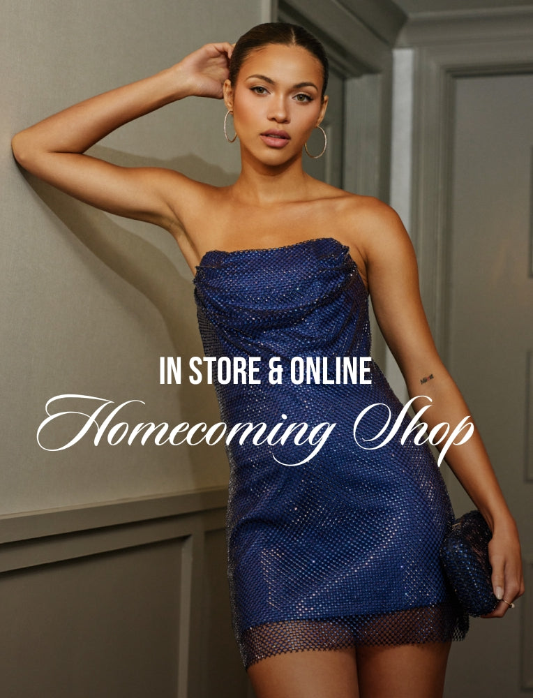 A woman posing in a strapless, shimmering royal blue mini dress with a sequined texture, holding a matching blue clutch. The image features a gray paneled wall background and has a text overlay reading 'IN STORE & ONLINE Homecoming Shop'.