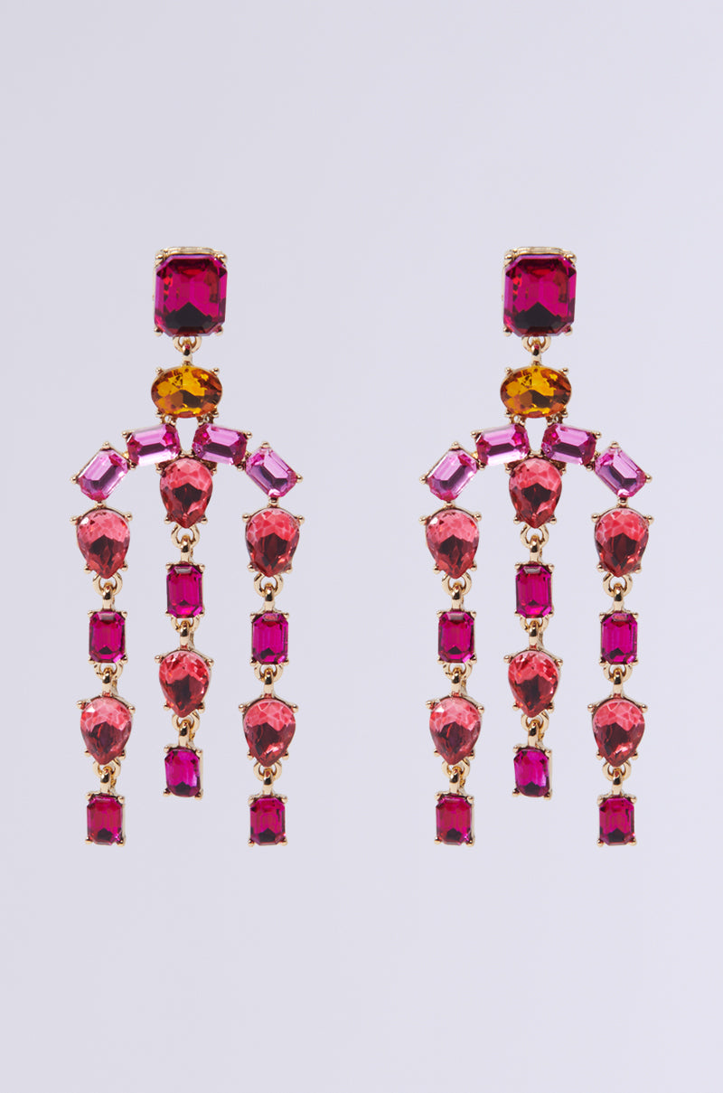 Introducing the PAINT THE TOWN EARRING: a stunning pair of chandelier-inspired earrings showcasing an array of vibrant pink and red gemstones in diverse shapes, all set in faux gold. Each earring is designed with a gemstone post at the top and features dangling geometric formations beneath it.