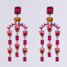 Introducing the PAINT THE TOWN EARRING: a stunning pair of chandelier-inspired earrings showcasing an array of vibrant pink and red gemstones in diverse shapes, all set in faux gold. Each earring is designed with a gemstone post at the top and features dangling geometric formations beneath it.