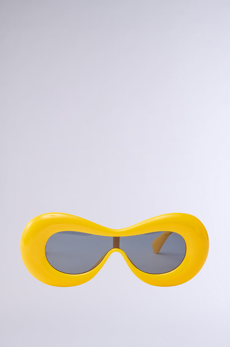 LITTLE BIT OF ZEST YELLOW SUNGLASSES feature a sleek, rounded design with dark lenses against a plain light gray background.