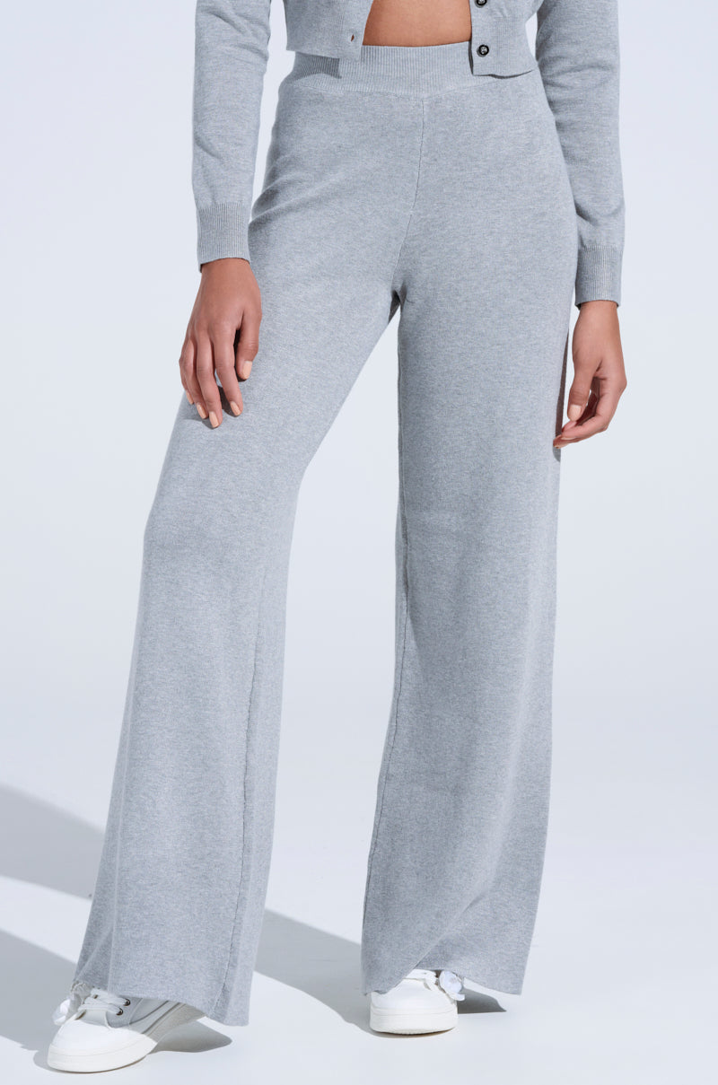 In a light gray long-sleeve top and COZY LUXE WIDE LEG PANT, paired with white sneakers, a person creates an effortlessly chic look on a plain white background. The soft texture of the clothing adds to the allure.