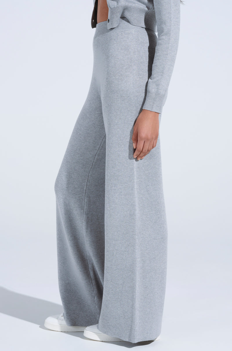 A person radiates cozy luxe vibes in COZY LUXE WIDE LEG PANT and matching cropped sweater, paired with white sneakers against a plain light gray background, standing sideways.