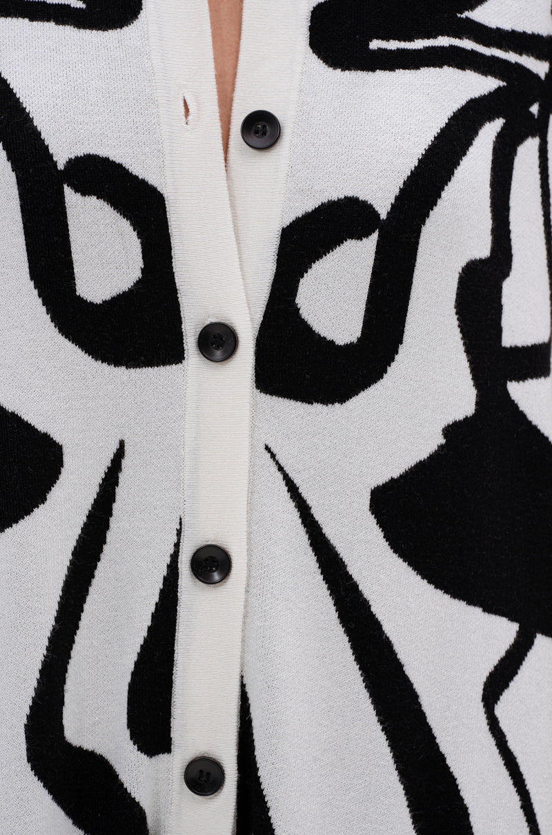 Close-up of the HAPPY HOUR PRINTED KNIT JUMPSUIT, a white knit piece with black abstract patterns and a row of five black buttons down the center.