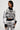 A woman stands confidently in the KALEIDOSCOPE DREAM PULL OVER SWEATER and matching pants, featuring an abstract wavy pattern. Her outfit's cropped silhouette complements her short hair as she poses with one hand on her hip against a plain background.