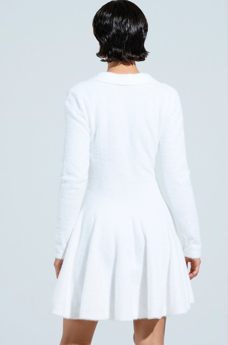 The woman with short black hair embodies the cozy girl chic look in the COZY GIRL CHIC FUZZY KNIT MINI DRESS WITH LONG SLEEVES, featuring a fitted bodice and flared skirt. Seen from behind against a light backdrop, her fluffy white dress exudes comfort and style.