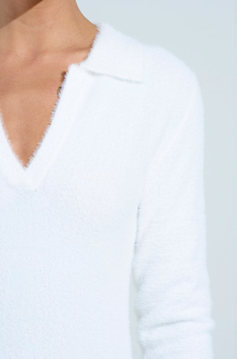 Clad in a COZY GIRL CHIC FUZZY KNIT MINI DRESS WITH LONG SLEEVES, the person epitomizes comfort and style in this image of their upper torso against a plain, light background.