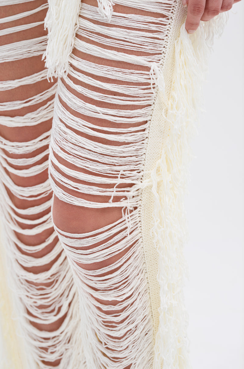 Close-up of the BEST DRESSED FRINGE BRALETTE AND LEGGING, featuring cream-colored pants with a stretchy waistband and horizontal fringed cutouts for an artistic, fashion-forward look.