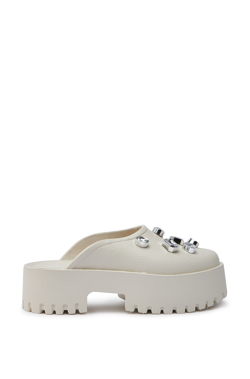 The AZALEA WANG HAIN IVORY RHINESTONE FLAT is a white flat shoe with rhinestone embellishments on the faux leather upper, a textured finish, and an open back design for a modern look.