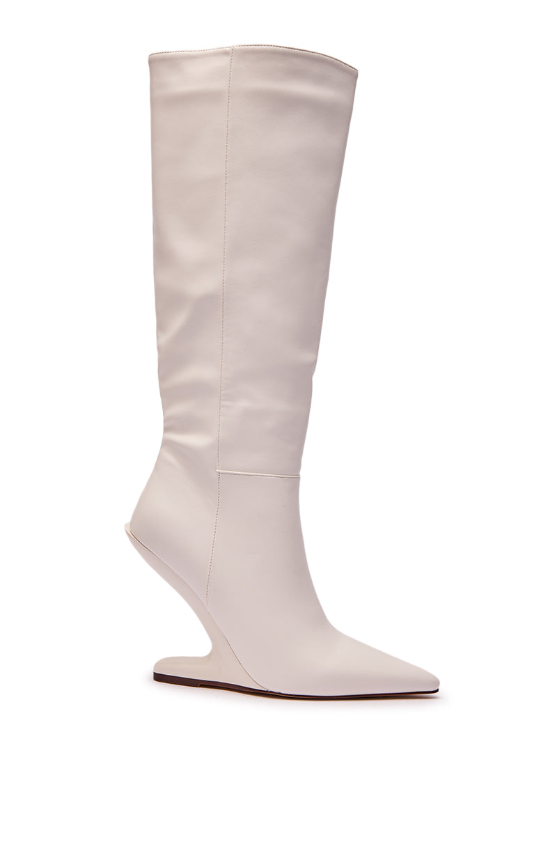 The AZALEA WANG HAKIM WHITE WEDGE BOOT is a tall, faux leather knee-high boot with a sculpted inward-curving wedge heel and pointed toe, shown against a plain white background.